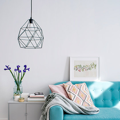 Geometric lampshade hanging beside blue couch